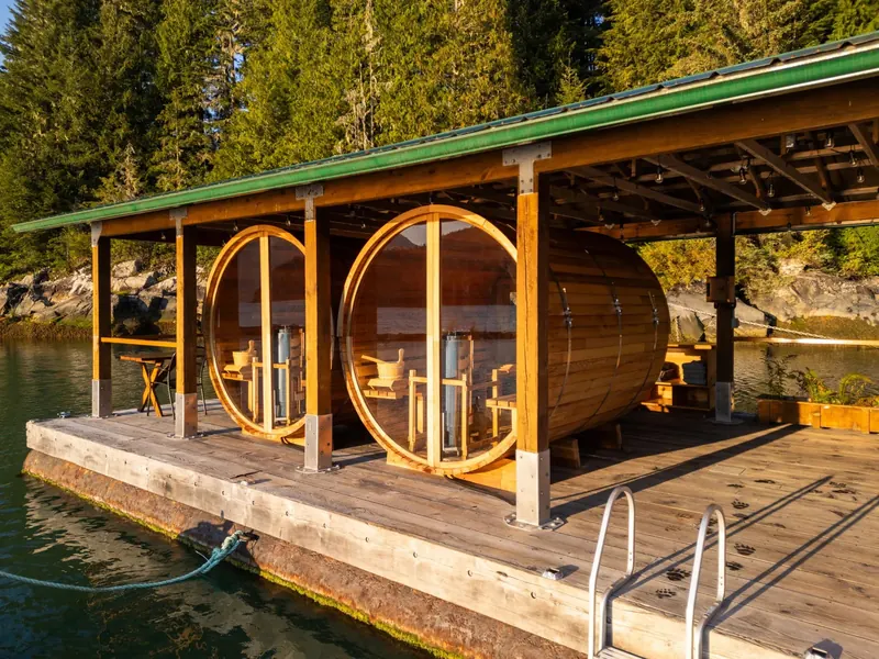 A barrel sauna with round glass ends sits on a covered float at the lodge.
