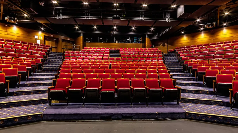 From the stage, rows of red seats climb toward the back of the theatre under rows of small lights.
