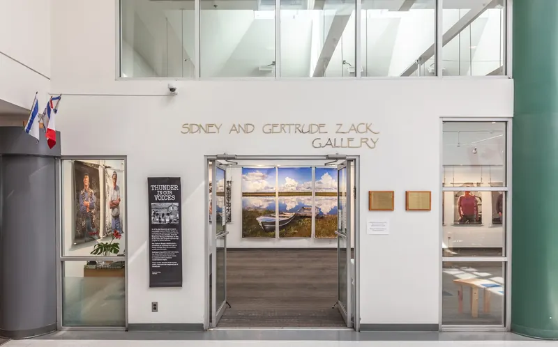 The doors of the Sidney and Gertrude Zack Gallery stand open beside a Thunder in Our Voices banner, and portraits hang on the walls inside.
